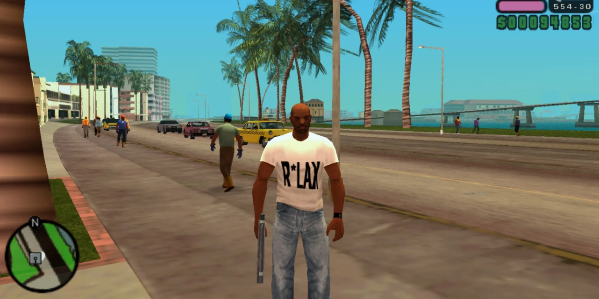 Victor Vance cầm súng trên con đường bờ biển đầy màu sắc của Vice City trong Grand Theft Auto: Vice City Stories trên PSP, mang đến trải nghiệm thế giới mở đầy đủ.